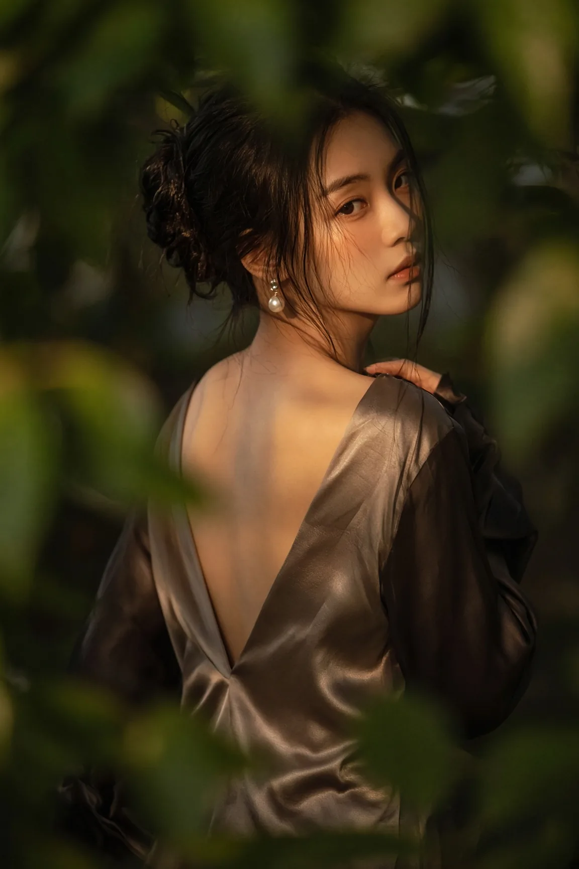Woman Looks Back Through Green Leaves